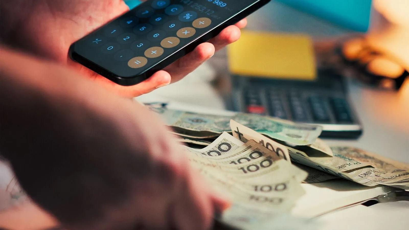 Cilvēks telefonā izmanto kalkulatoru, plānojot izdevumus