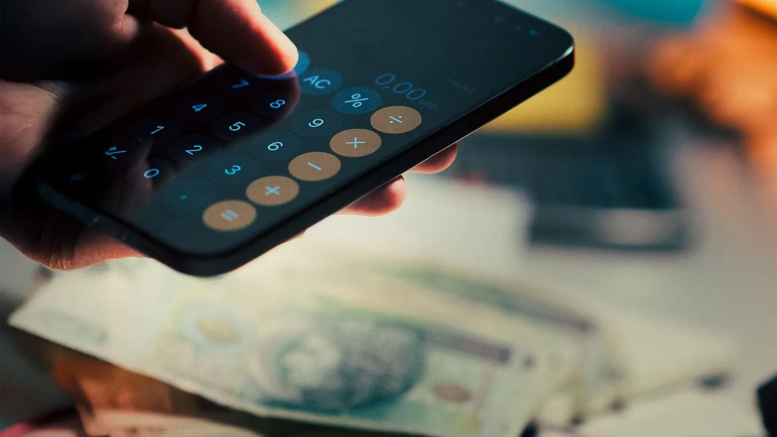 Cilvēks telefonā pieraksta un aprēķina izdevumus